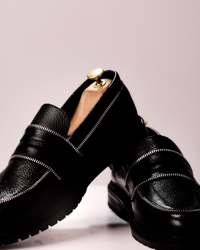 who-we-are Stylish black leather loafers with gold accents for a classy, modern look.