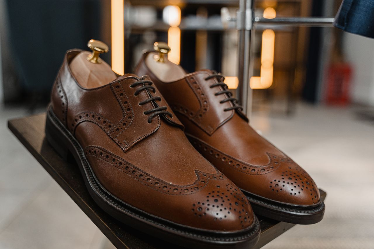 about-us Classic brown leather brogue shoes with detailed perforations on a stylish display.
